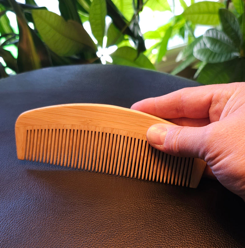 Hand holding a bamboo comb