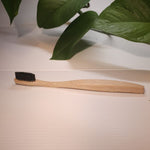 A bamboo toothbrush with a wooden handle and black bristles