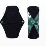 Two reusable menstrual pads, one unbuttoned laid flat and one buttoned closed 
