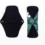 Two reusable menstrual pads, one unbuttoned laid flat and one buttoned closed 