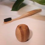 bamboo holder with toothbrush in background 