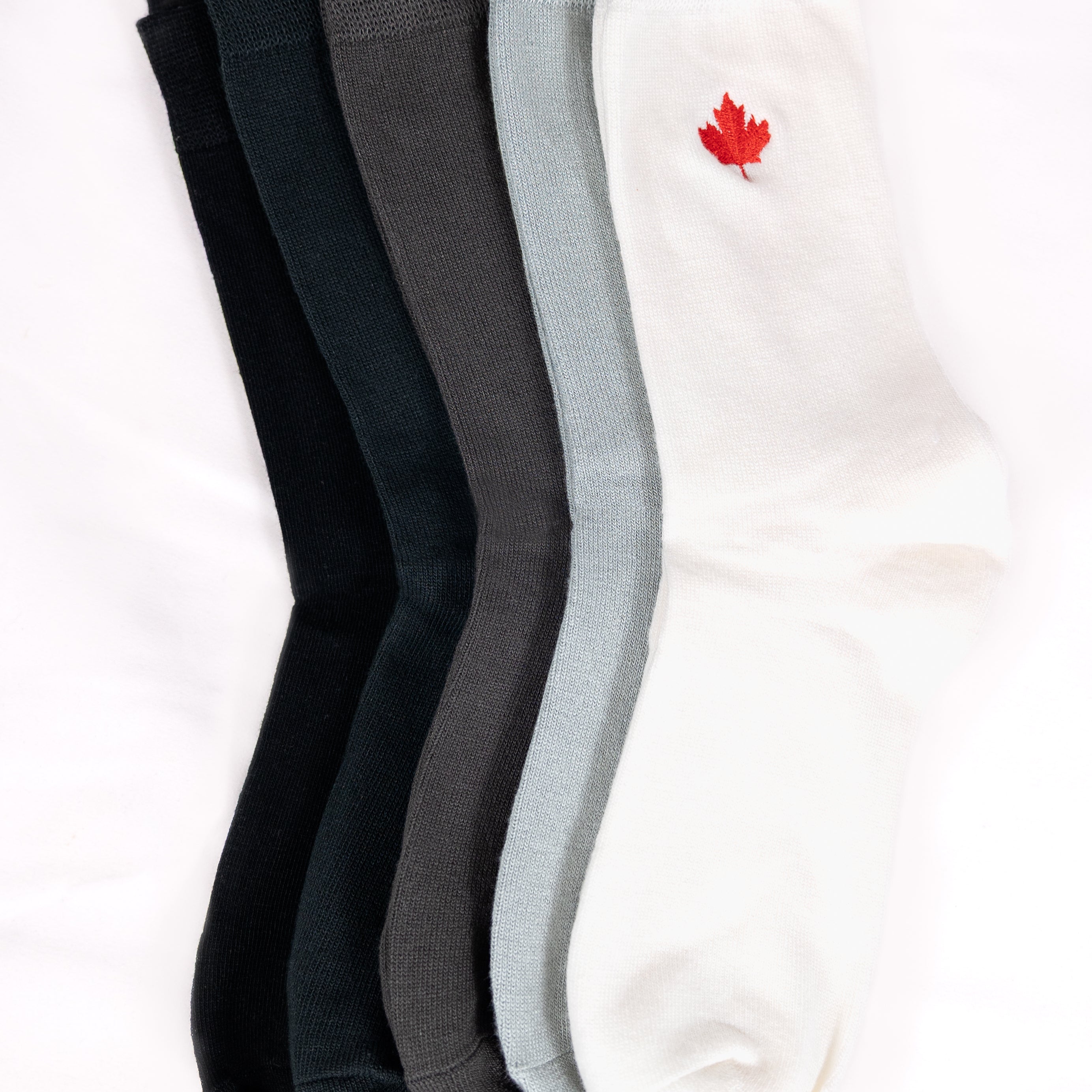 five pairs of socks in black, dark grey, gray, and white with a red maple leaf logo 